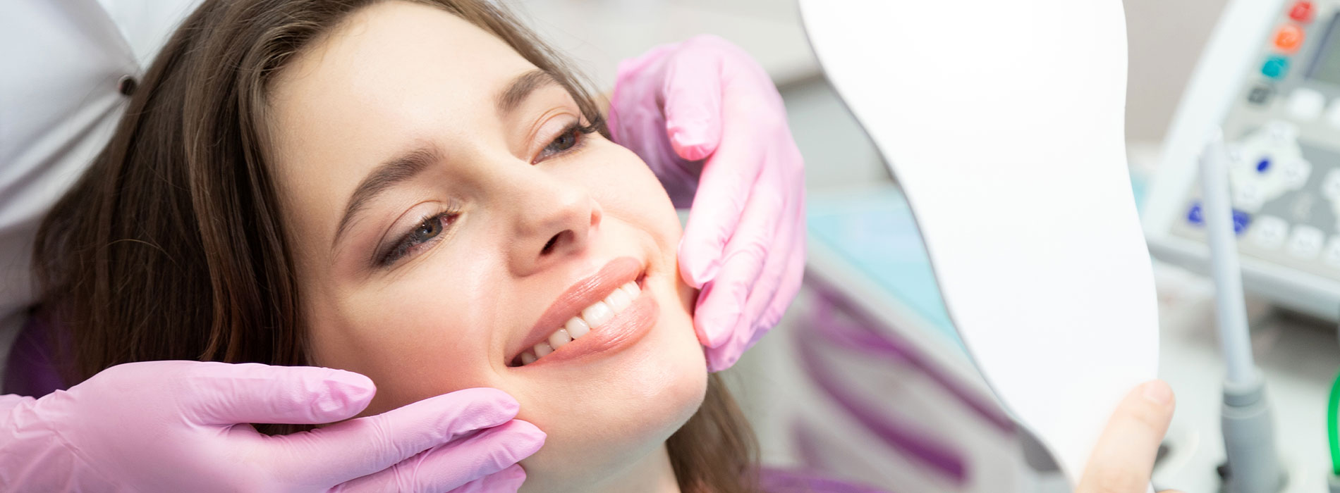 A woman receiving dental care with her mouth open, while seated in a dentist s chair, with a dental hygienist performing the procedure.