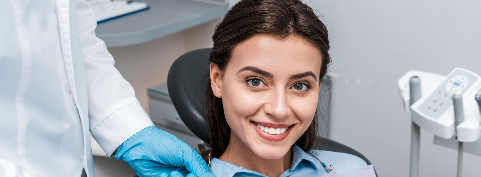 Woman sitting in dental chair with smiling expression, receiving dental care from professional.