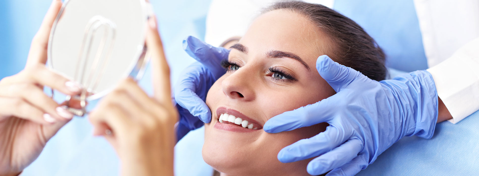 A woman sitting in a dental chair with a dentist examining her teeth.