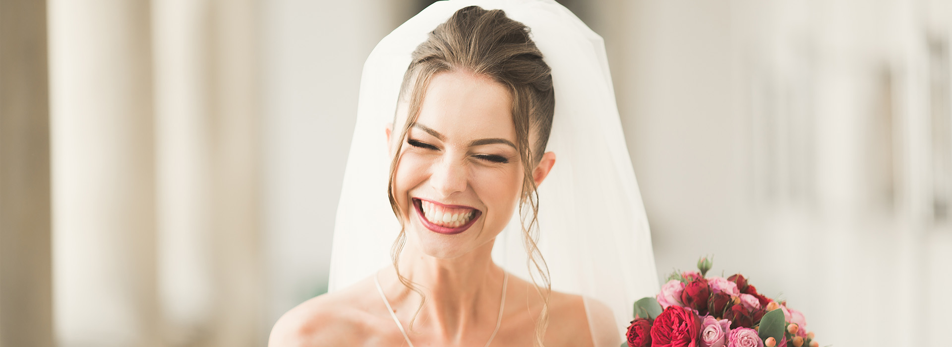 A woman wearing a white bridal veil and smiling at the camera.