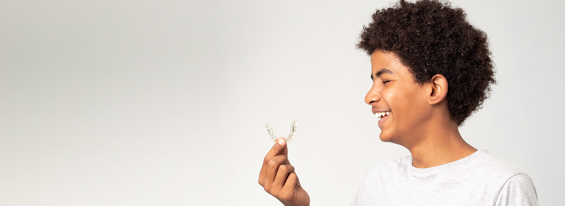 The image features a young person holding a white bird in their hand with a joyful expression, set against a plain background.