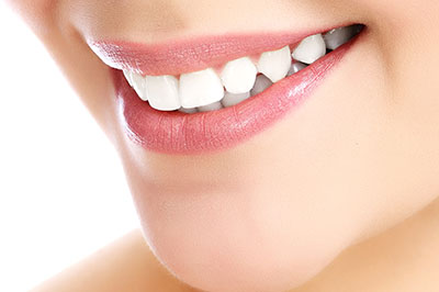 The image features a close-up of a person s face with a focus on their teeth, showcasing a bright smile and the use of cosmetic dental treatments.