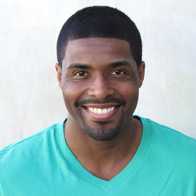 The image shows two older adults, a man and a woman, sitting closely together with smiles on their faces, embracing each other against a backdrop of a scenic outdoor setting.