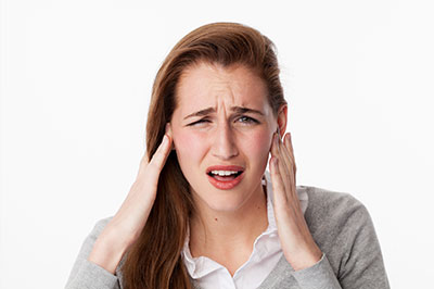 The image shows a woman with her hand on her head, appearing to be in pain or discomfort, with a concerned expression.