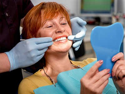 A woman in a dental chair receiving dental treatment with a smile on her face.