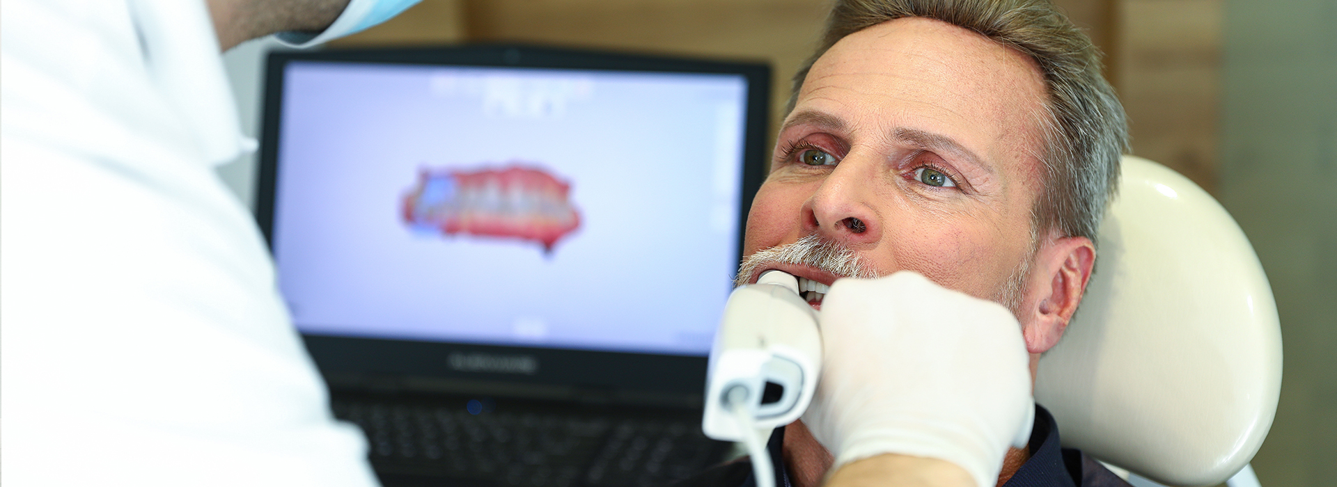 A man receiving dental treatment with a hygienist attending to him.