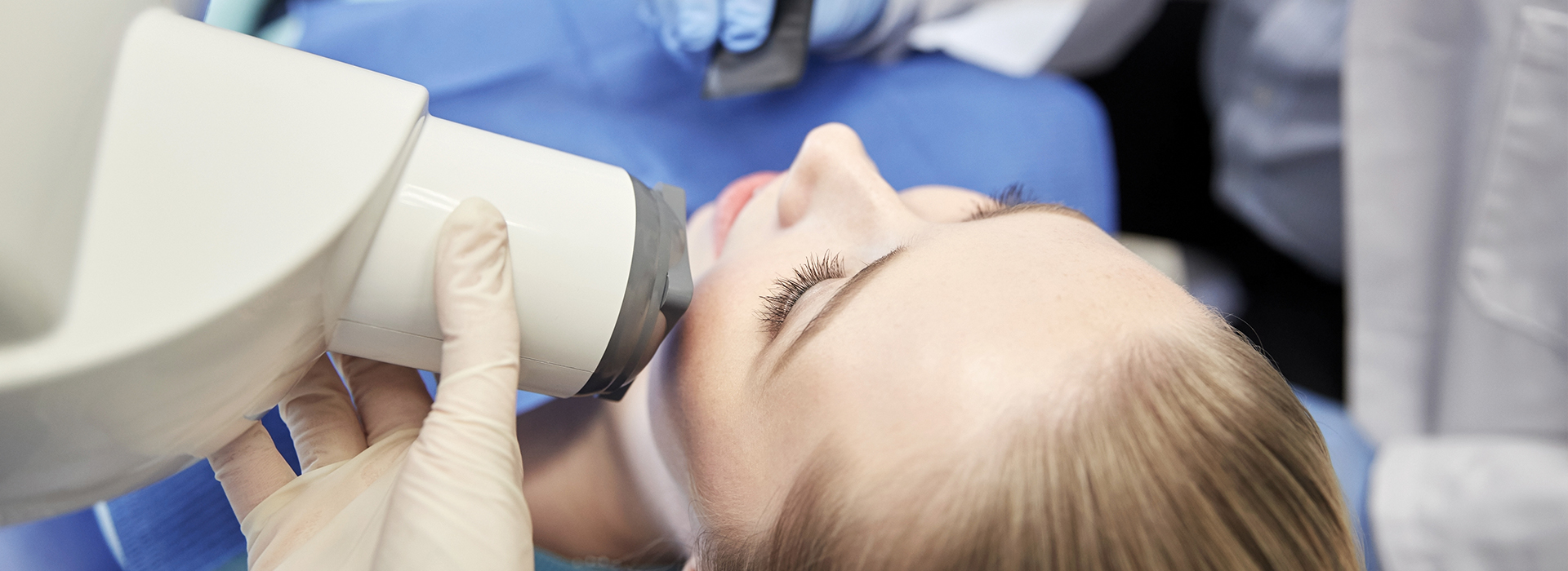 A woman receiving medical attention with a dental device on her face, likely during a dental procedure.