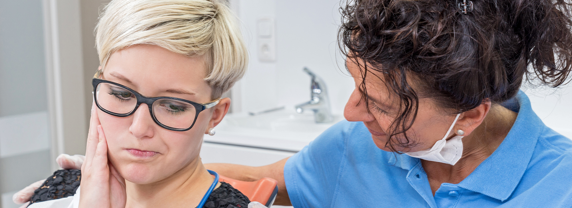 A photograph features two individuals engaged in a dental care activity  one person appears to be receiving treatment while seated in a dental chair, and another individual stands nearby, possibly assisting or observing.