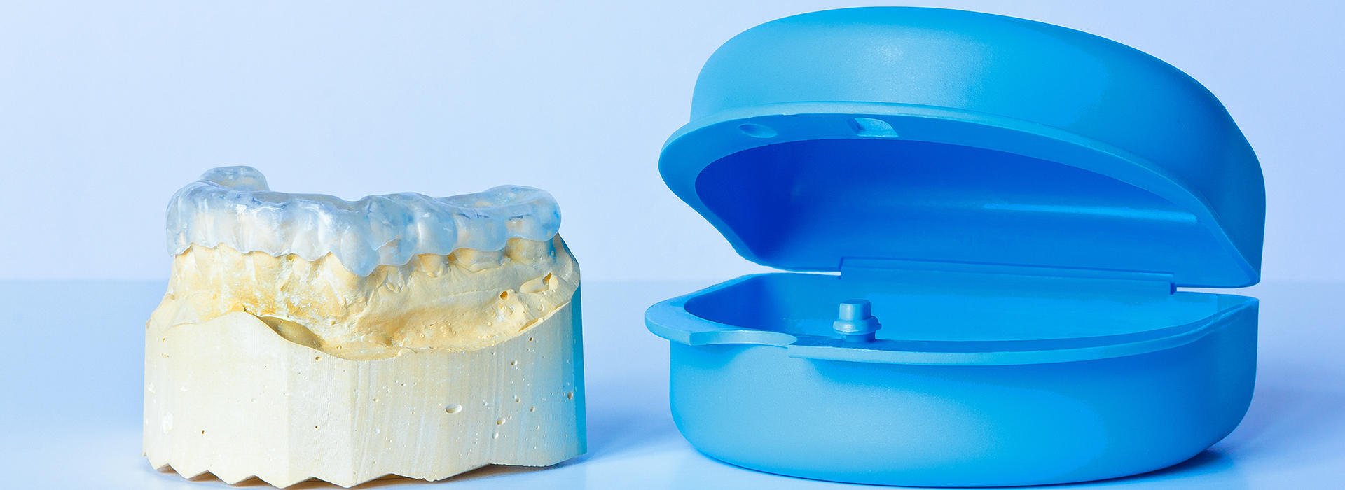 The image shows two blue dental implants placed next to each other on a white background, with one appearing larger than the other due to perspective.