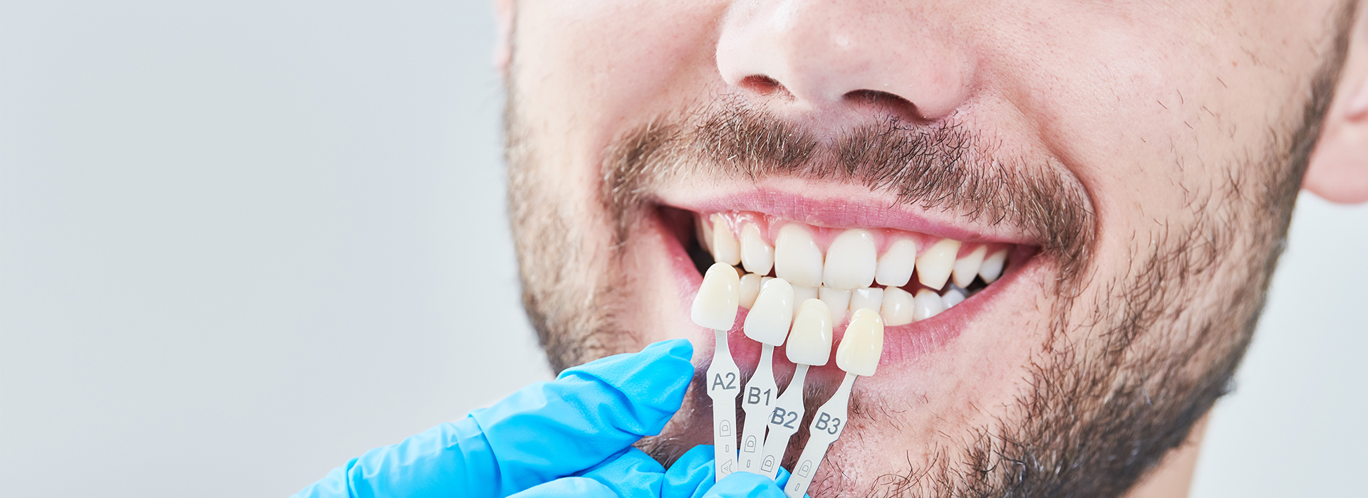 A man with a toothbrush in his mouth, wearing gloves and a blue apron, smiling at the camera.