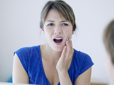 A woman with her mouth open appears surprised while looking at her reflection in a mirror.