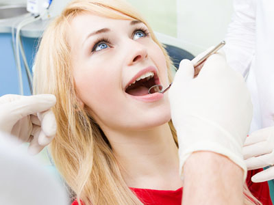 A woman receiving dental care with a dentist performing treatment.