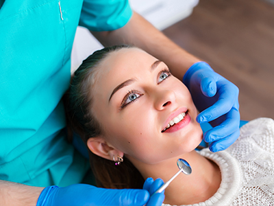 A dental professional performing a procedure on a patient s teeth with a smile.