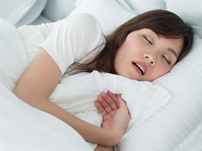 A woman lying in bed with her eyes closed, appearing to be asleep.